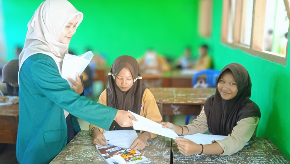 Leni Suciati, mahasiswa PBSI Universitas Nurul Huda, membimbing siswa kelas 7A SMP Negeri 1 Tambakboyo saat uji coba soal Bahasa Indonesia Kurikulum Merdeka, Jumat (21/11/2025).